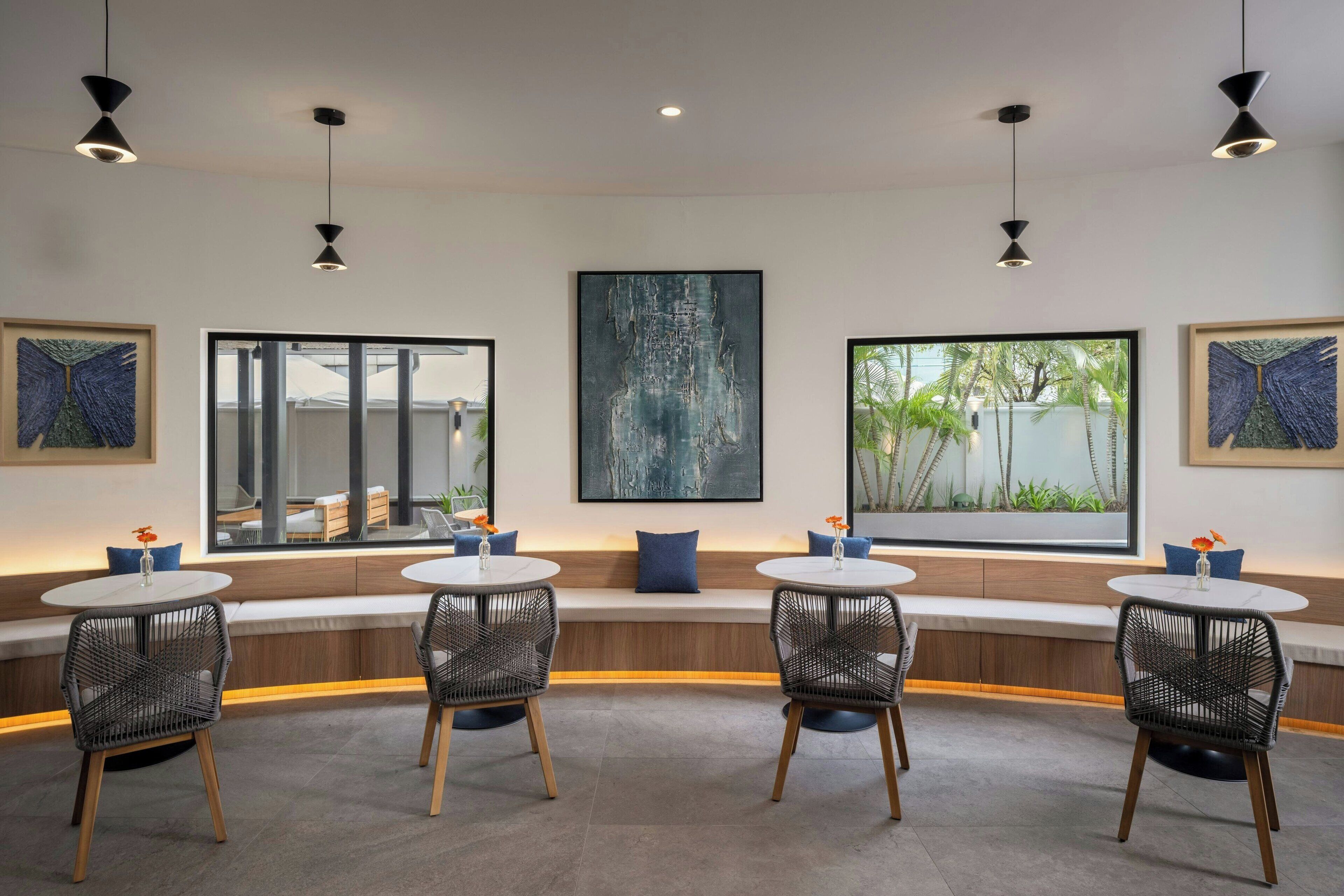 A modern interior with a curved seating area, round tables, and black pendant lighting.