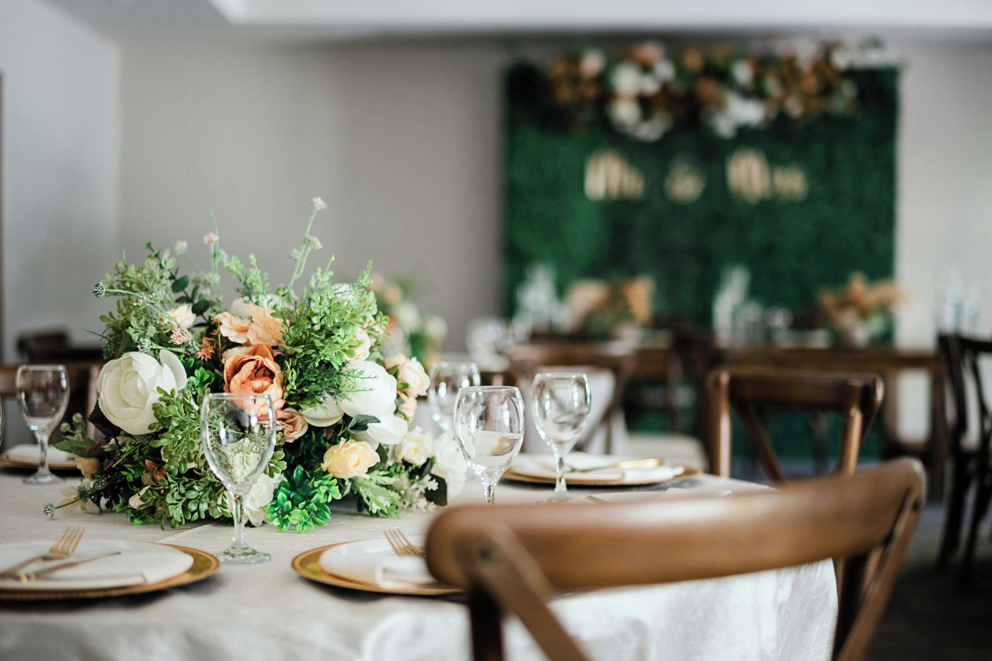 Une table dressée pour un repas formel, agrémentée d’un centre de table floral, de verres à vin et de couverts.