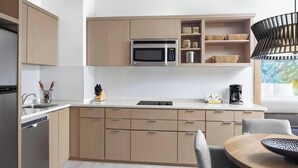 A modern kitchen with wooden cabinets, a built-in microwave, and a dining area with a round table and chairs.