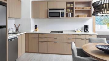 Eine moderne Küche mit Holzschränken, einer eingebauten Mikrowelle und einem Essbereich mit einem runden Tisch und Stühlen.