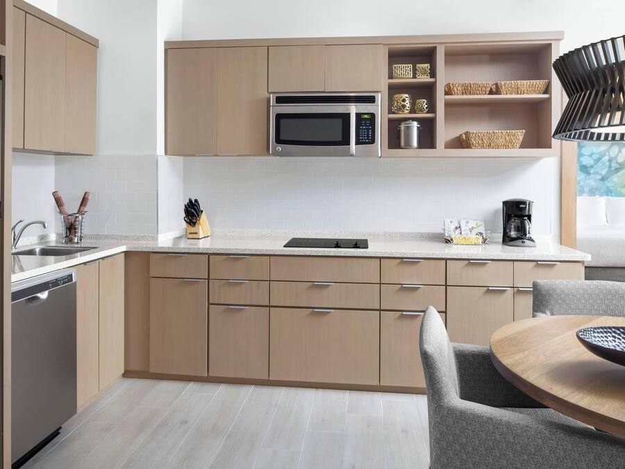 Eine moderne Küche mit Holzschränken, einer eingebauten Mikrowelle und einem Essbereich mit einem runden Tisch und Stühlen.