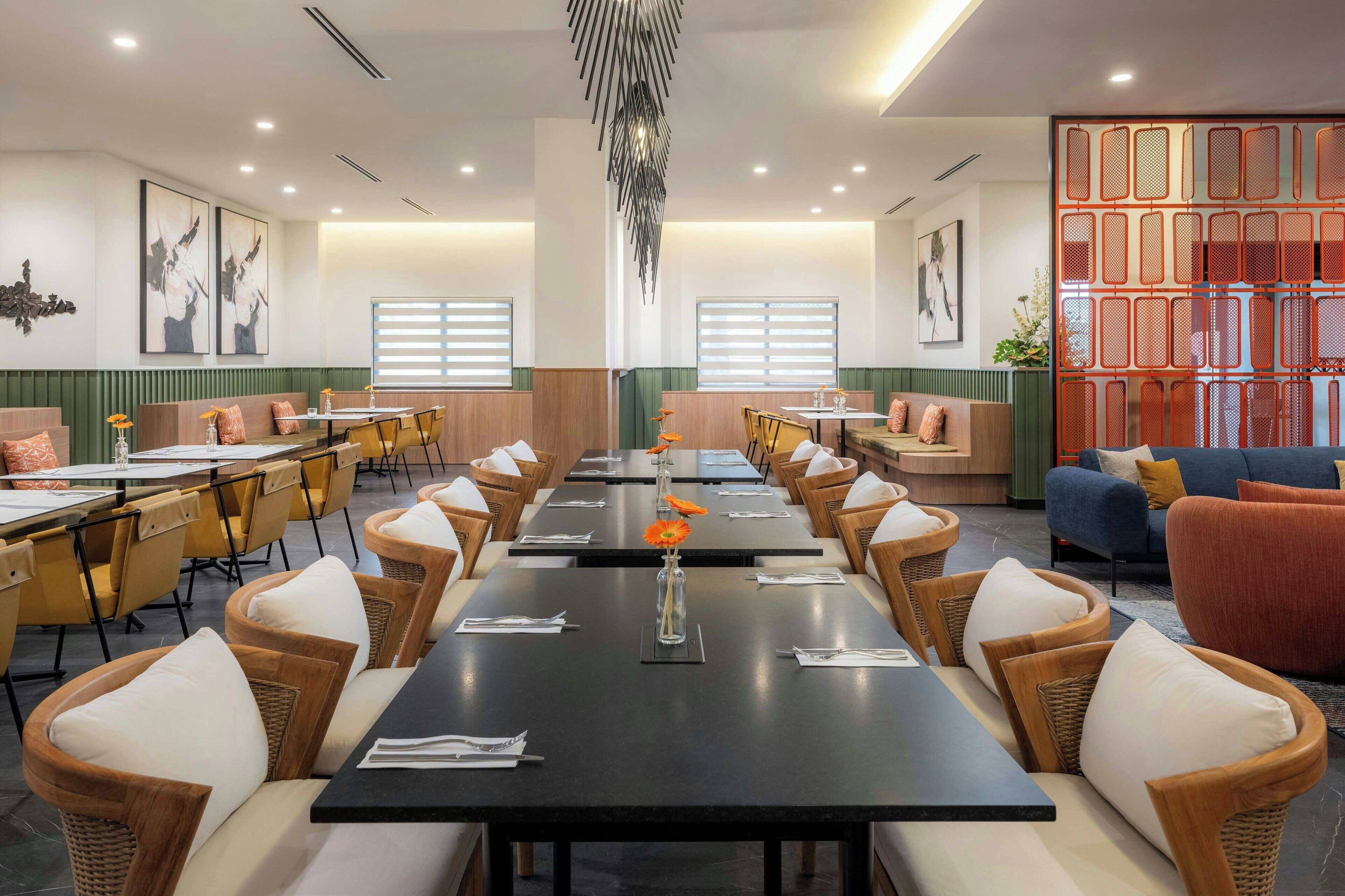 A conference room with long tables, wicker chairs, and a decorative hanging light fixture.