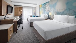 Habitación de hotel con dos camas, un escritorio, un televisor y un mural abstracto grande en la pared.