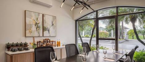 A modern conference room with a large table, chairs, and a view of palm trees through large windows.