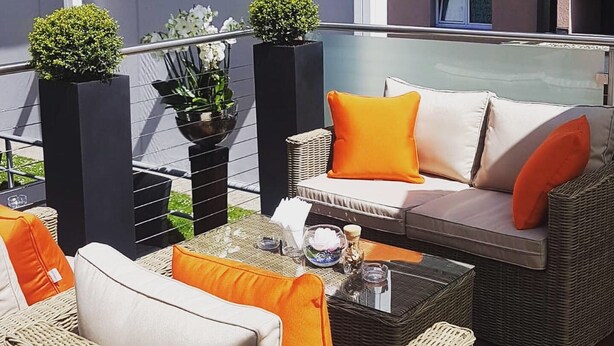 A balcony with wicker furniture, a glass table, and potted plants. - Hotel Sommerau-Ticino (Dietikon)
