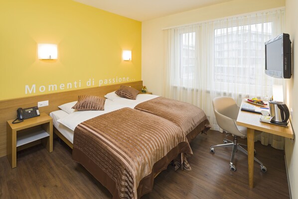 A hotel room with two beds, a desk with a computer, a chair, and a TV. - Hotel Sommerau-Ticino (Dietikon)