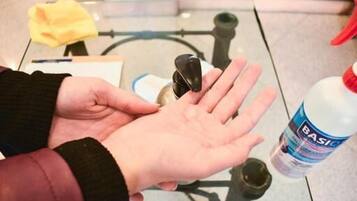 Una persona sosteniendo un dispensador de gel antibacterial y un vaso.