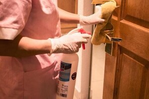 Una persona limpiando una puerta de madera con un trapo y un atomizador.
