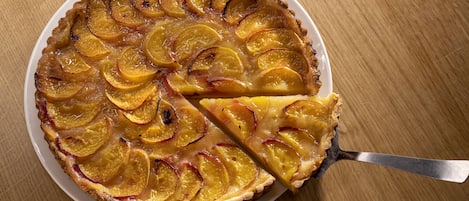 A round pie with a golden-brown crust, sliced and arranged in a circular pattern, on a white plate.