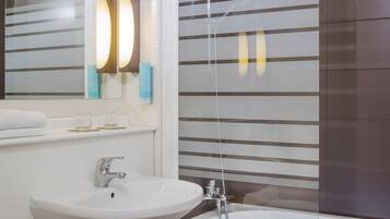 Une salle de bain avec un lavabo blanc, un miroir et une cabine de douche.