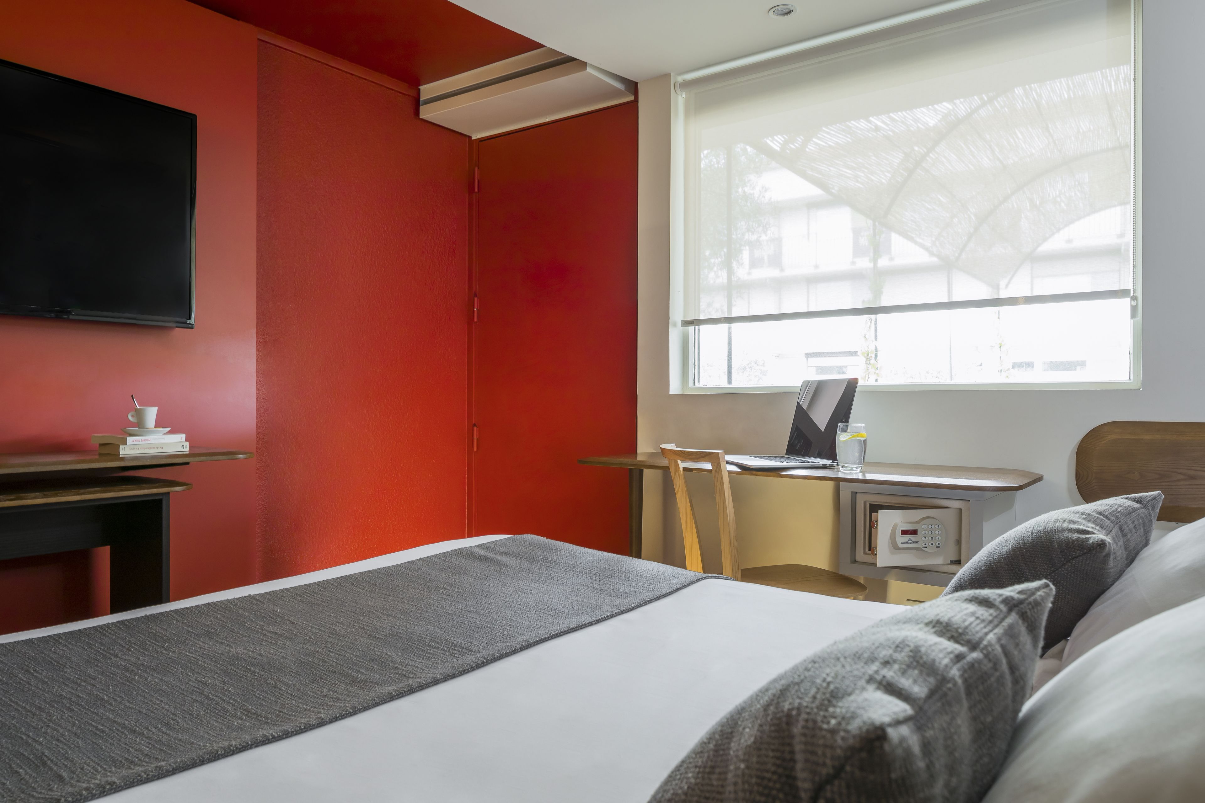 Une chambre d’hôtel équipée d’un lit, d’un bureau, d’une chaise, d’une télévision et d’une fenêtre donnant sur un paysage agréable.