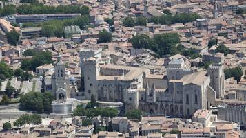 A historic cityscape with a prominent cathedral featuring Gothic architecture, surrounded by dense urban buildings and greenery.