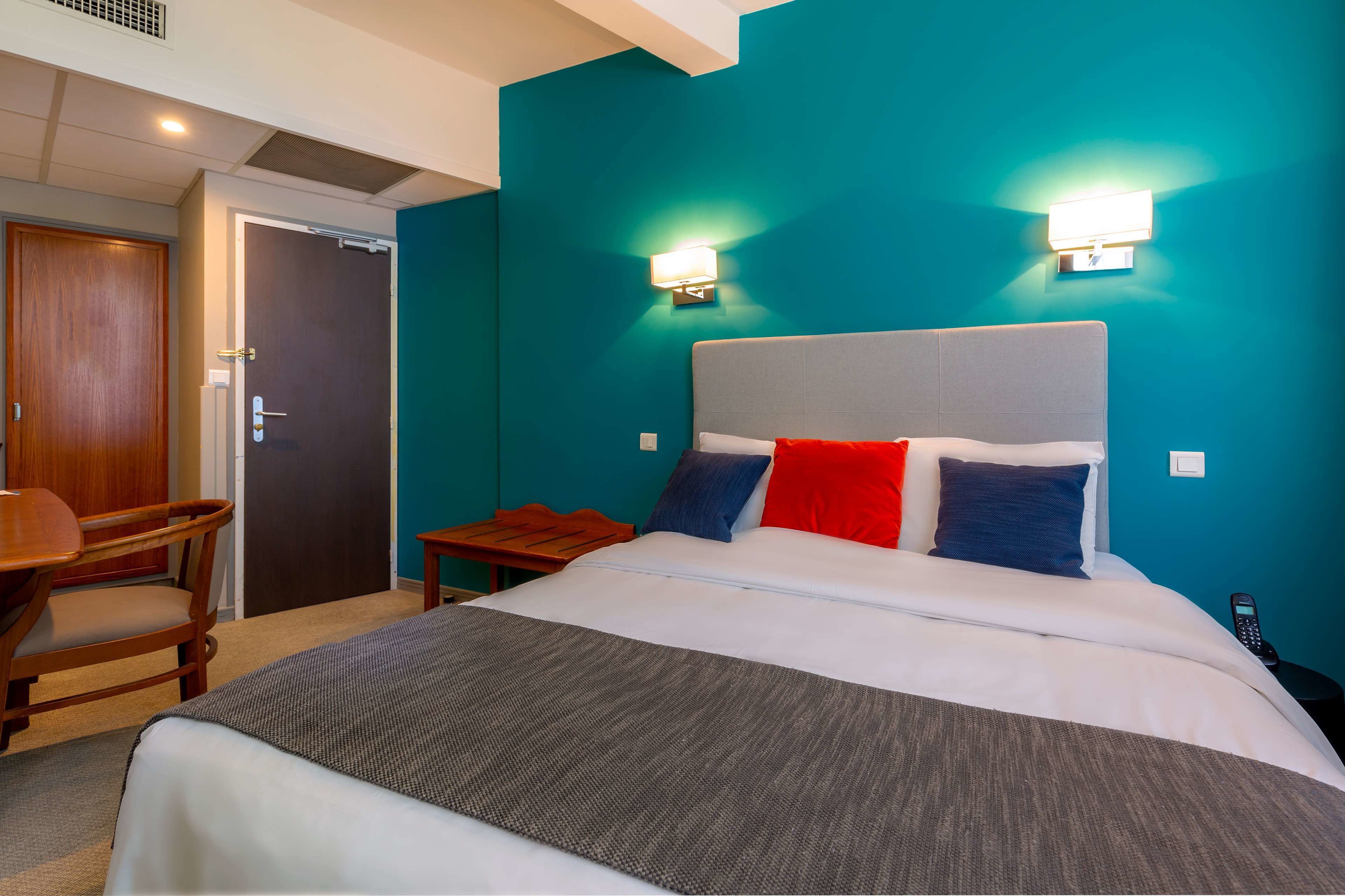 A hotel room with a bed, a desk, and a chair.