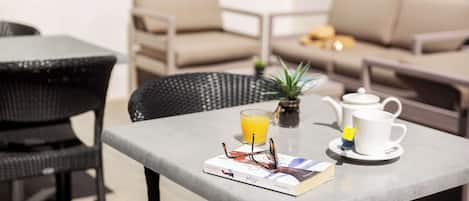 A cozy seating area with a table set for breakfast, including a book, glasses, a teapot, and a cup.