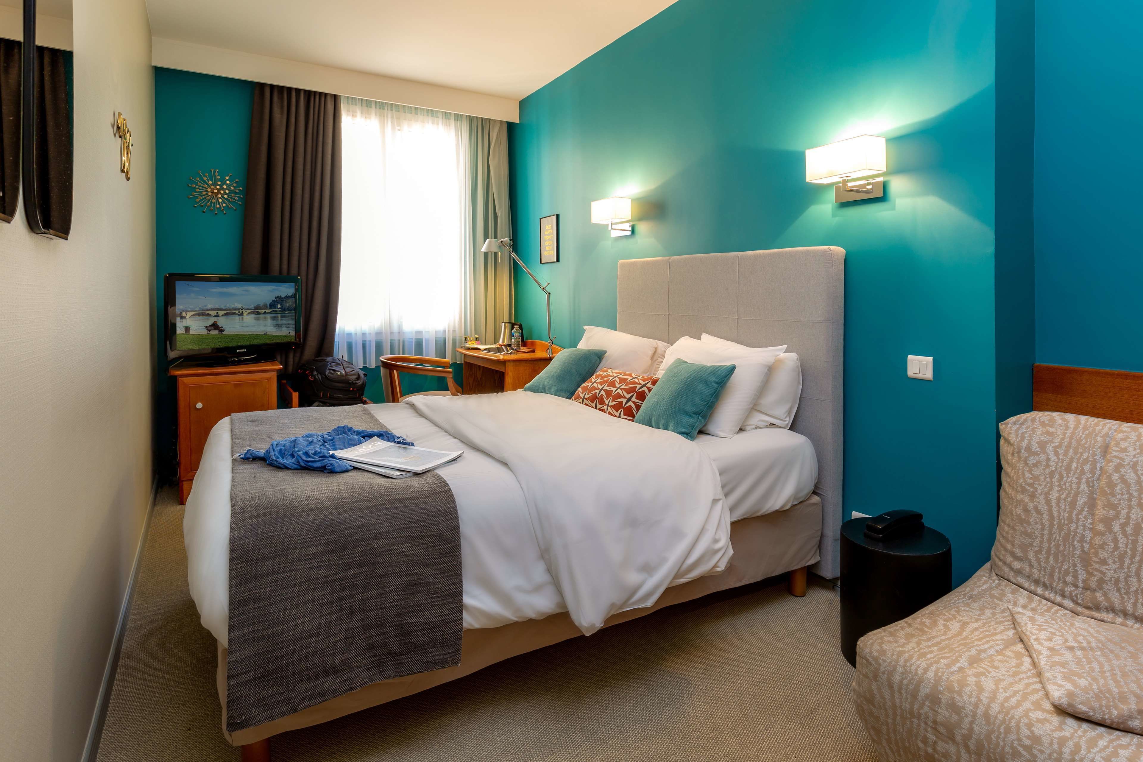 Una habitación de hotel con cama, televisor, escritorio y silla.