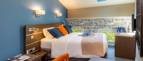 Una habitación de hotel con cama, mesita de noche, silla y escritorio.