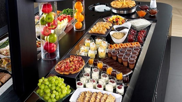 A buffet spread with various food items including fruits, pastries, and desserts.