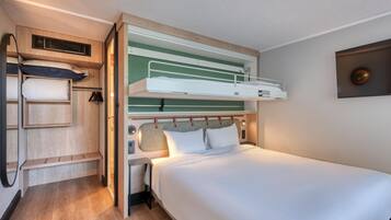 A bunk bed with a desk and shelving unit, a small table, and a wall-mounted TV.