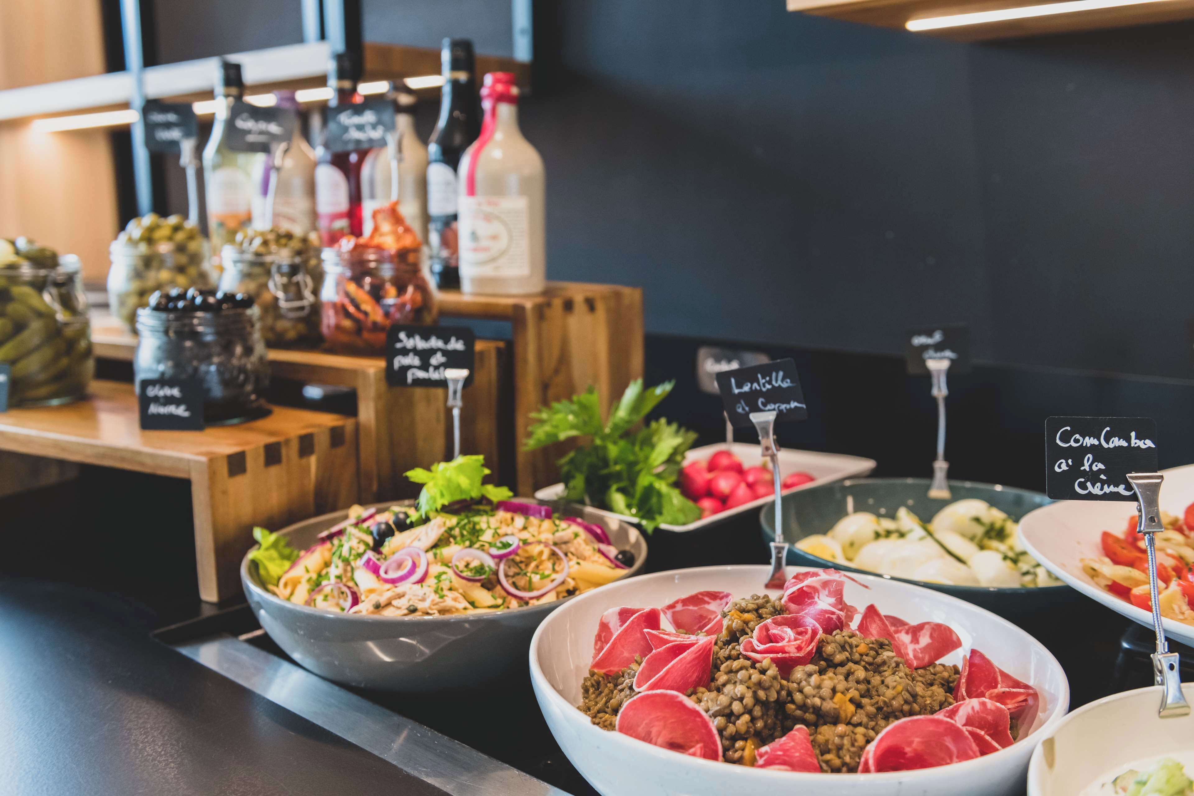 A buffet with various dishes including salads, meats, and condiments.