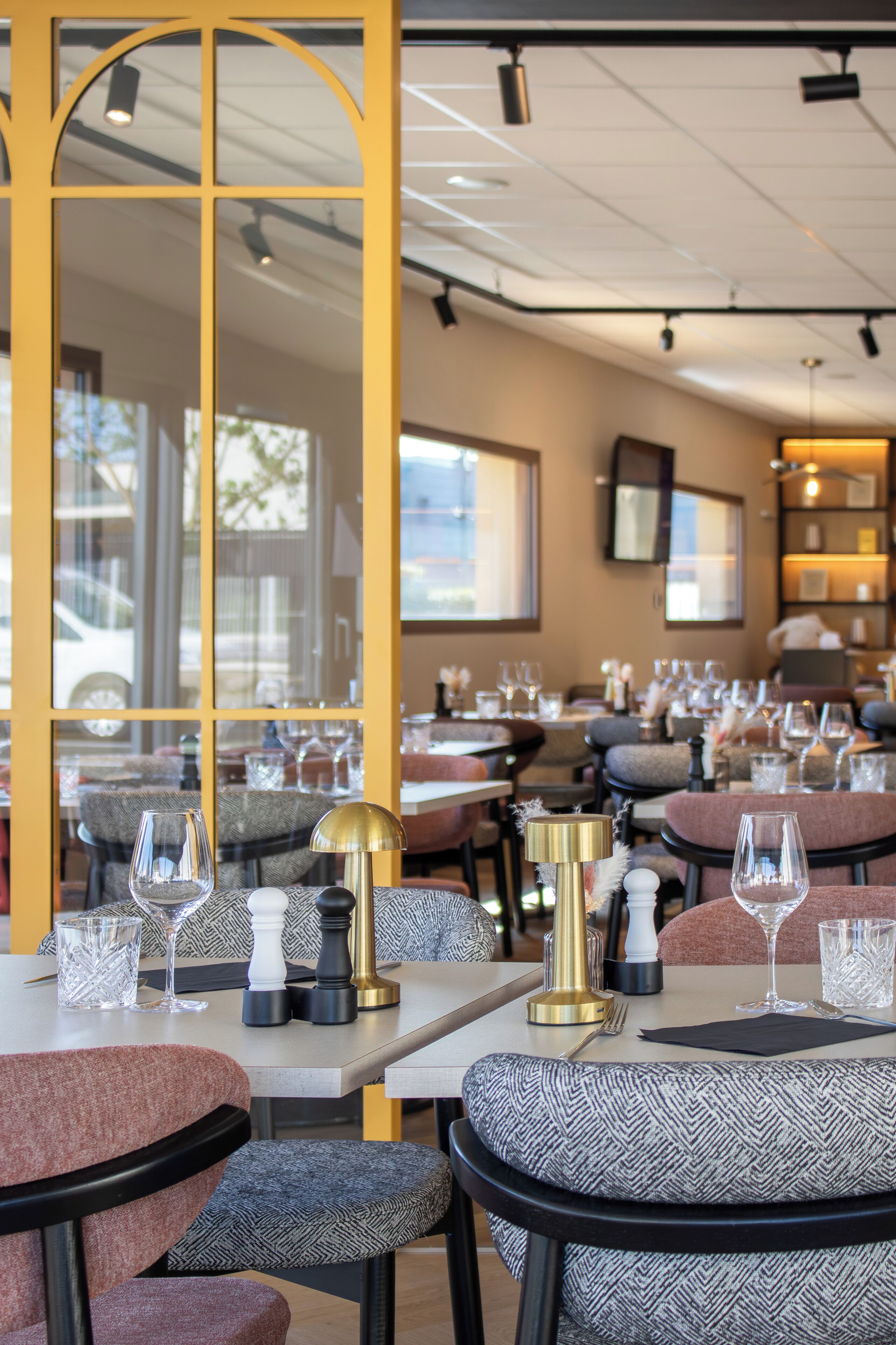 A restaurant interior with tables set for dining, chairs, and a large mirror.