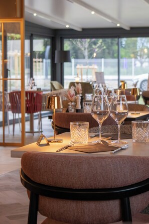 A dining area with a table set for four, featuring wine glasses, cutlery, and a lamp. - Brit Hotel Avignon Sud (Avignon)