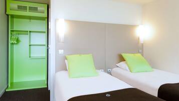 Une chambre d’hôtel avec deux lits, chacun doté d’un oreiller vert, d’une armoire verte et d’une tête de lit blanche.