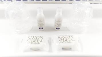 A white shelf with two bottles labeled 'Ylang Ylang Vetiver' and two sachets labeled 'Savon Vegetal Naturel'.