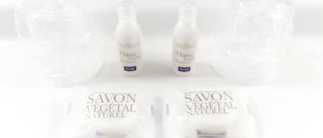 Een witte plank met twee flessen met de tekst 'Ylang Ylang Vetiver' en twee zakjes met de tekst 'Savon Vegetal Naturel'.
