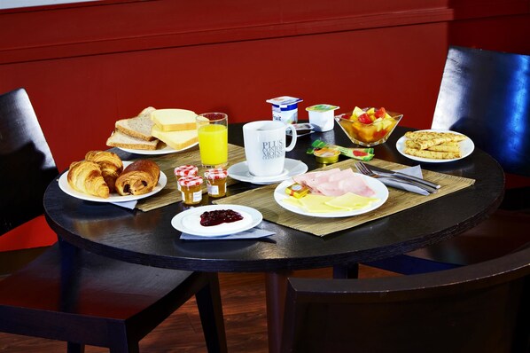 A breakfast table with croissants, toast, fruit, yogurt, and a coffee cup. - Kyriad Angers Pont De Ce (Les Ponts-de-Ce)