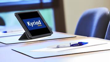 A tablet displaying 'Kyriad Hotel' on a desk with a pen and a notebook.