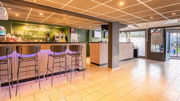 A bar area with stools, a counter with glassware, and a tiled floor.