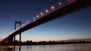 Un puente al atardecer con luces a lo largo de su estructura, cruzando un cuerpo de agua.