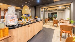 Un café moderne avec un comptoir central, une variété de plats et de boissons au menu, et un espace où l’on peut s’asseoir, avec des tables et des chaises.