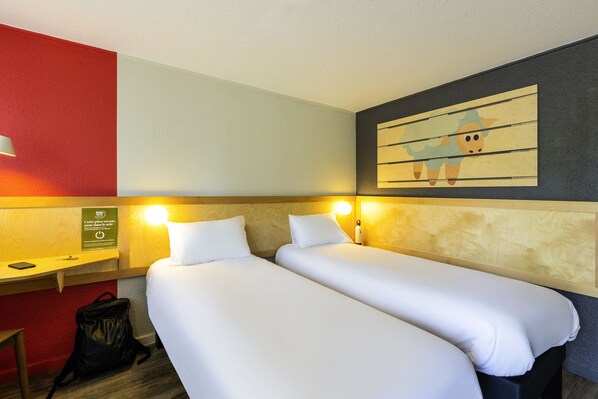 A hotel room with two beds, a desk, and a wall-mounted artwork.
