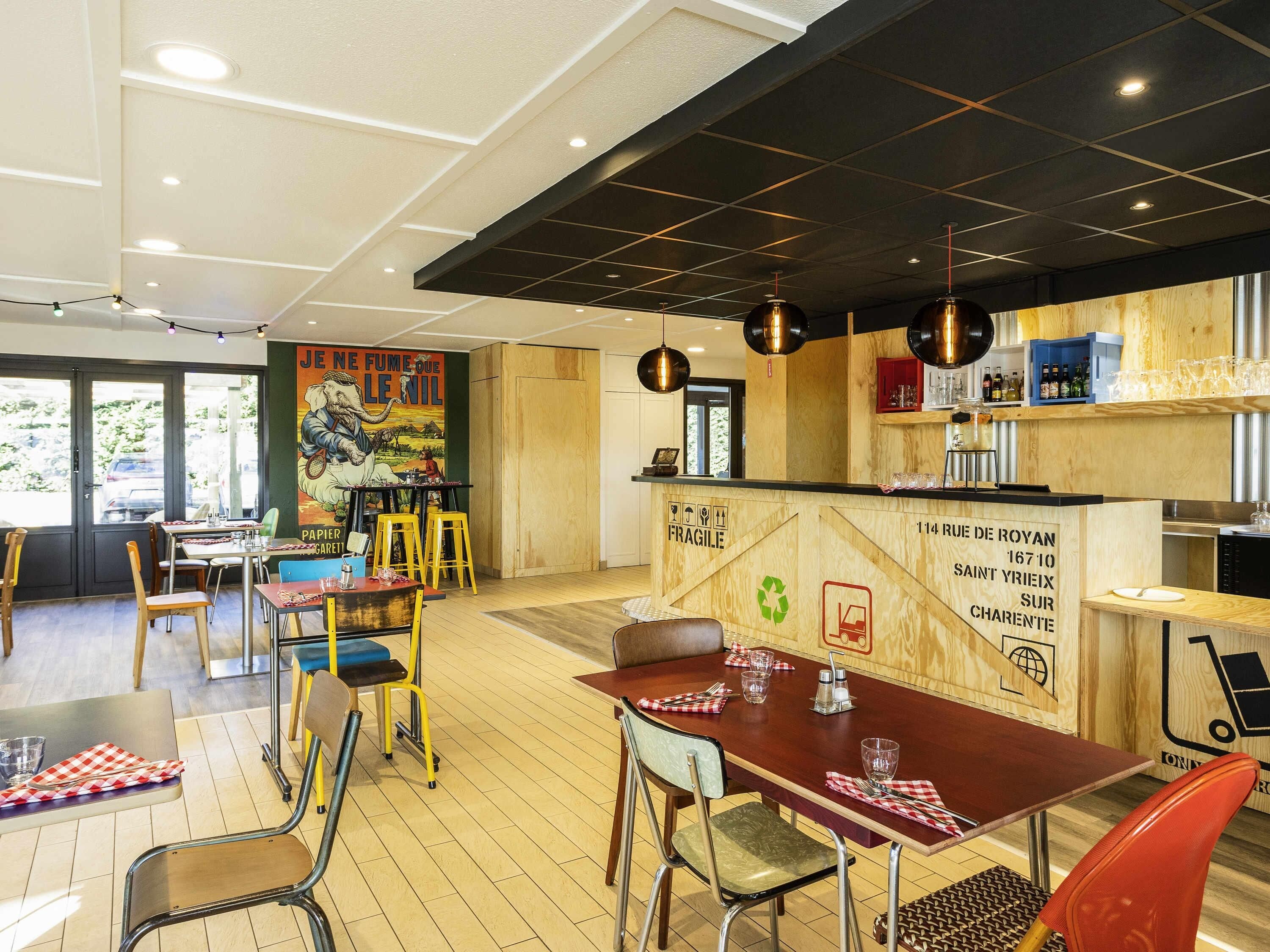 Interior de restaurante con piso de madera, mesas, sillas y una zona de bar.