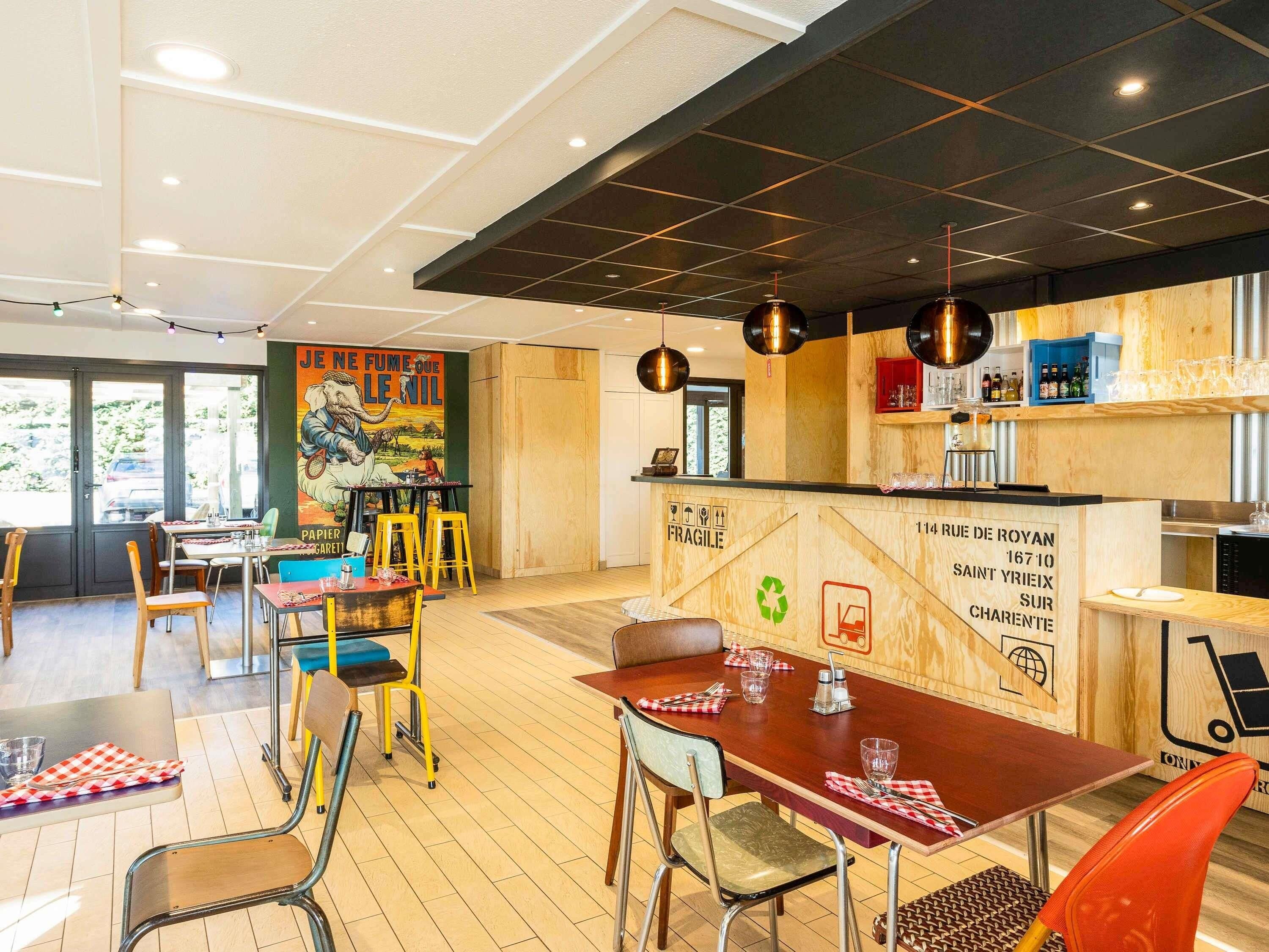 A restaurant interior with a wooden bar, multiple tables, and chairs.