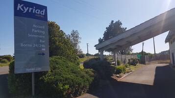 A sign for the Kyriad Hotel indicating amenities such as a bar, parking, and a 24/24h service.
