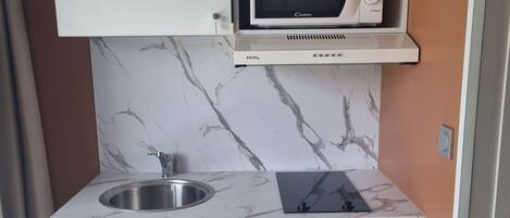 Cocina compacta con microondas integrado, fregadero y lavavajillas.