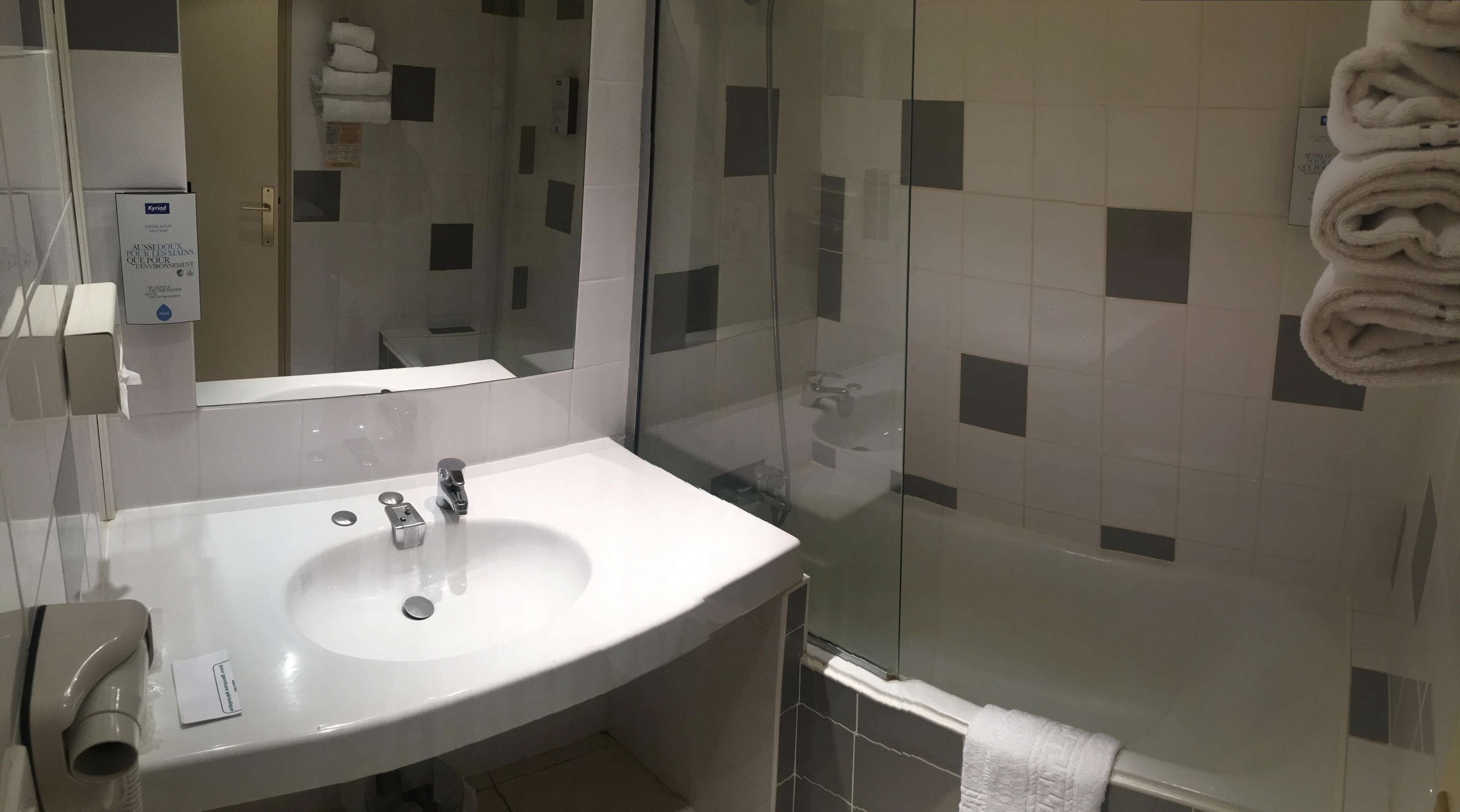 A bathroom with a white sink, a glass shower enclosure, and a towel rack with folded towels.