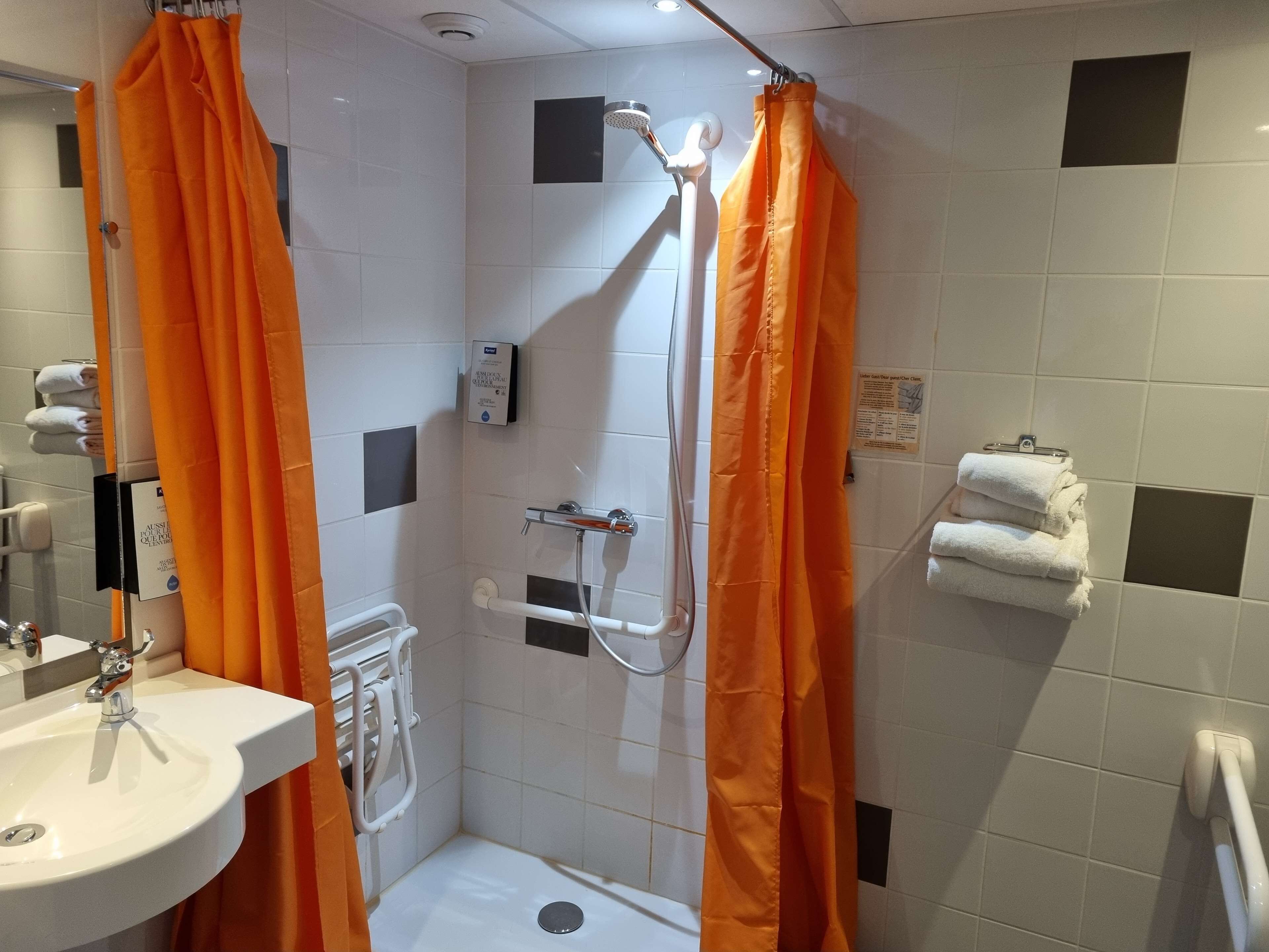 A bathroom with a shower, a sink, and a towel rack.