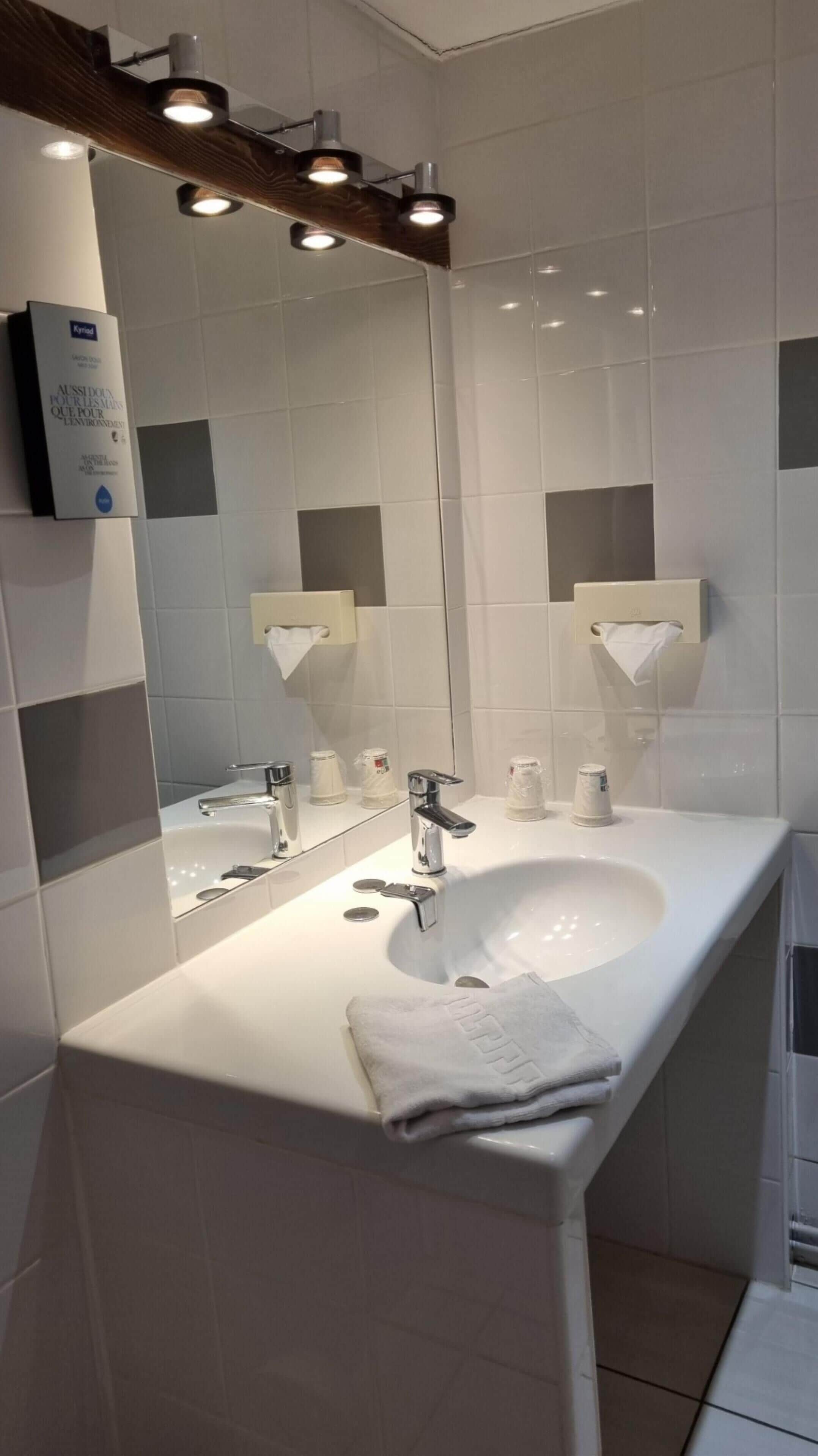 Une salle de bain moderne avec un lavabo blanc, un miroir et une serviette.
