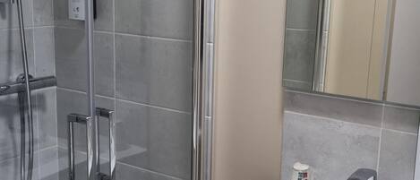 Une salle de bain moderne avec une douche à parois de verre, un lavabo blanc et un miroir au-dessus du lavabo.