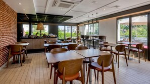 Een restaurant met bakstenen muren, houten tafels en stoelen, en grote ramen met uitzicht op het omliggende landschap.