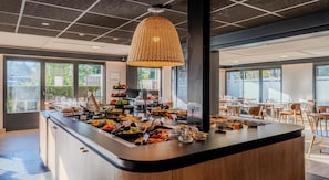 Un buffet de petit-déjeuner proposant une variété d’aliments et une grande fenêtre laissant entrer la lumière naturelle.