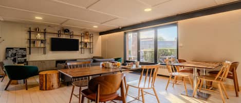 A modern dining area with a bar, seating, and a large window.
