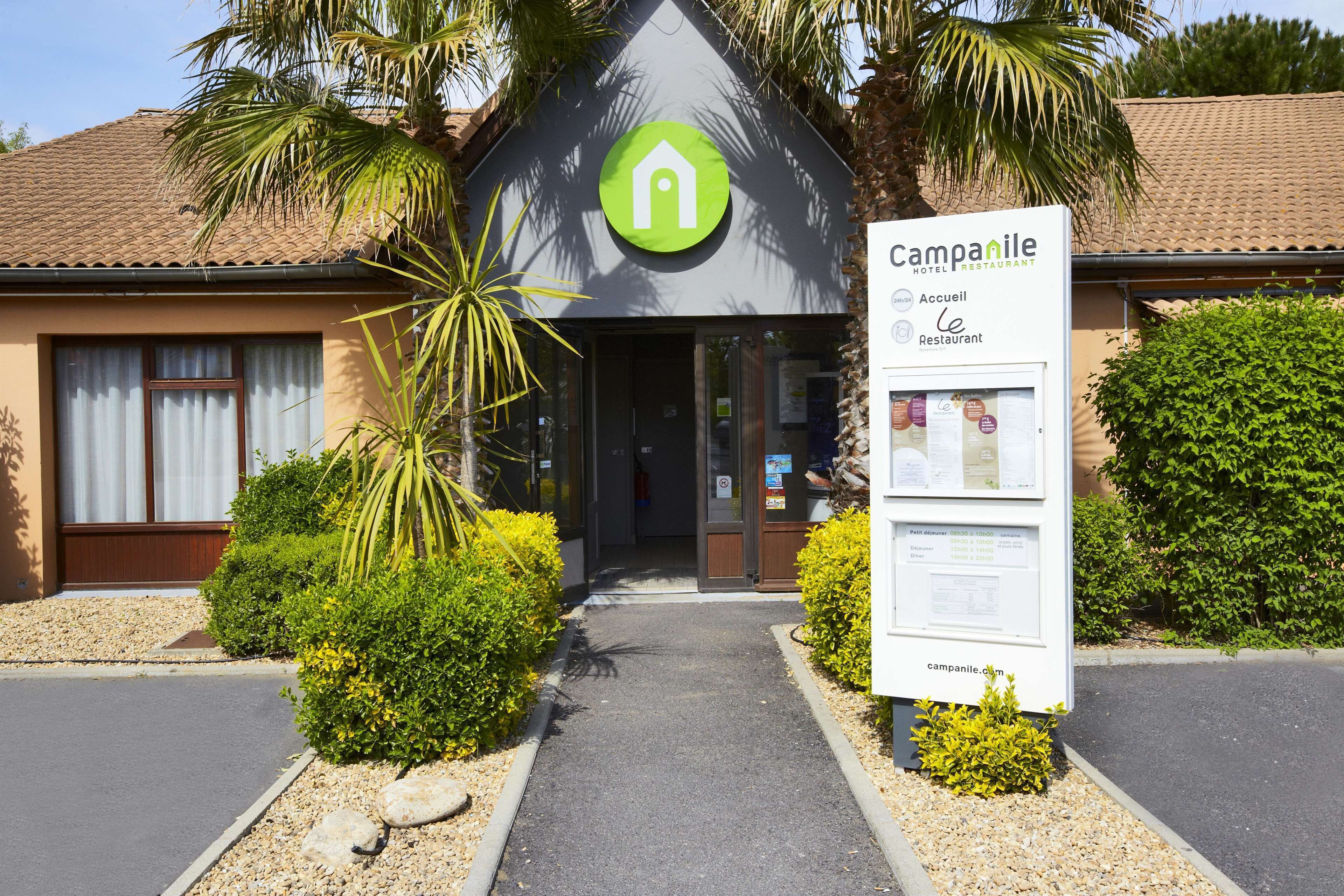 A hotel entrance with a modern design, a logo, and a signboard.