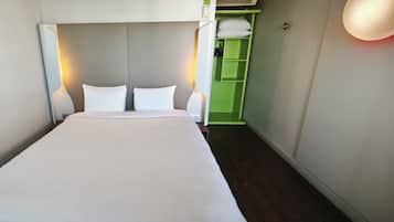 Una cama bien tendida con sábanas blancas en una habitación de hotel.