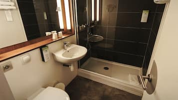 Un baño pequeño con un lavamanos blanco, un espejo, un inodoro y una cabina de ducha.