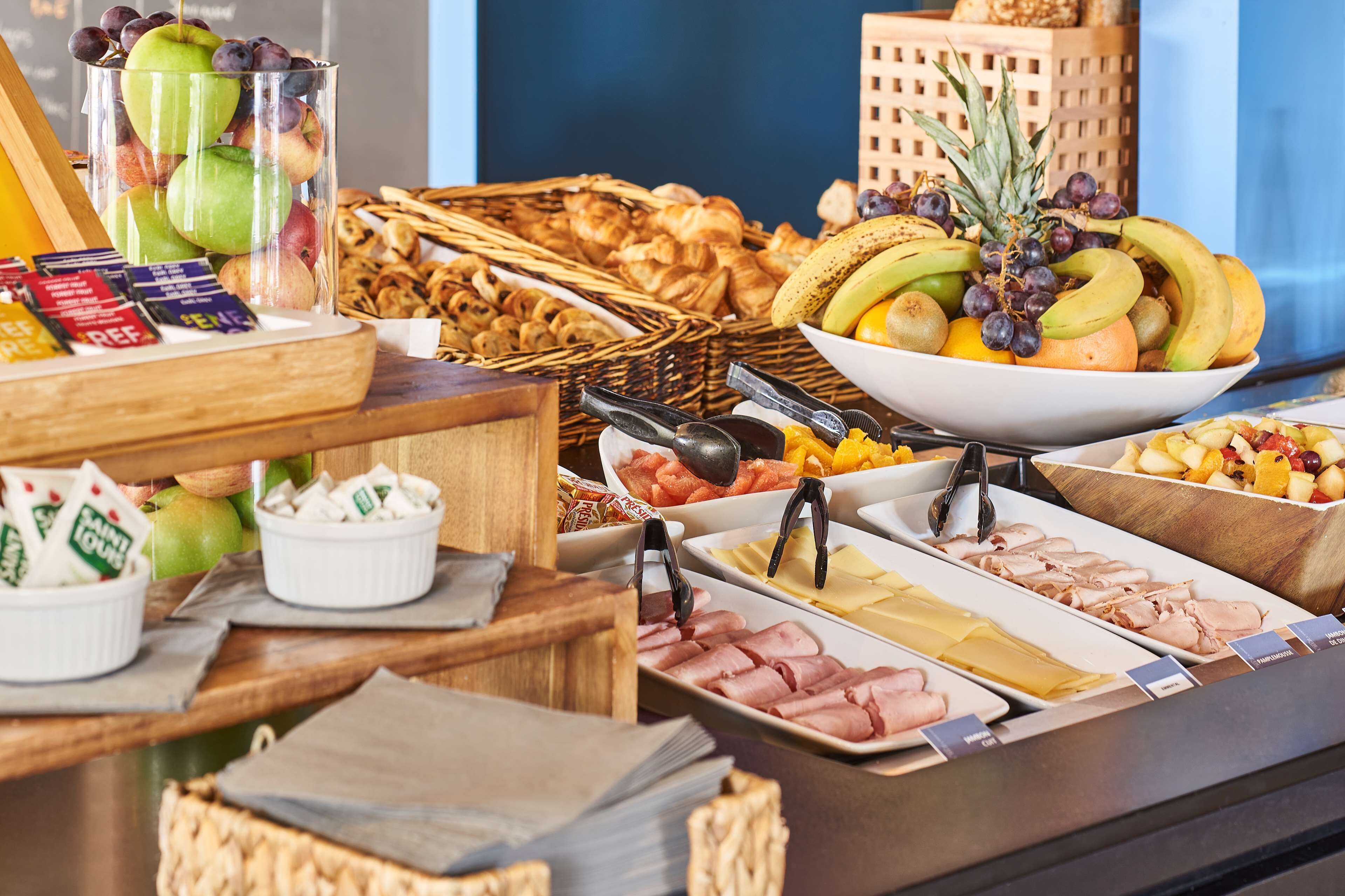 A buffet with various food items including fruits, pastries, and meats.