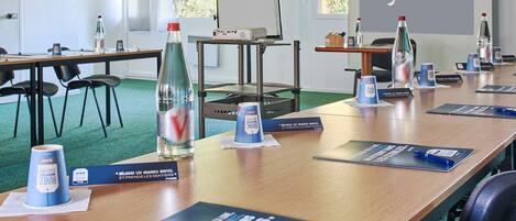 Une salle de conférence dotée d’un grand écran de projection affichant le mot « Kyriad », d’une longue table sur laquelle sont disposés des porte-noms, des bouteilles d’eau et des brochures d’information.
